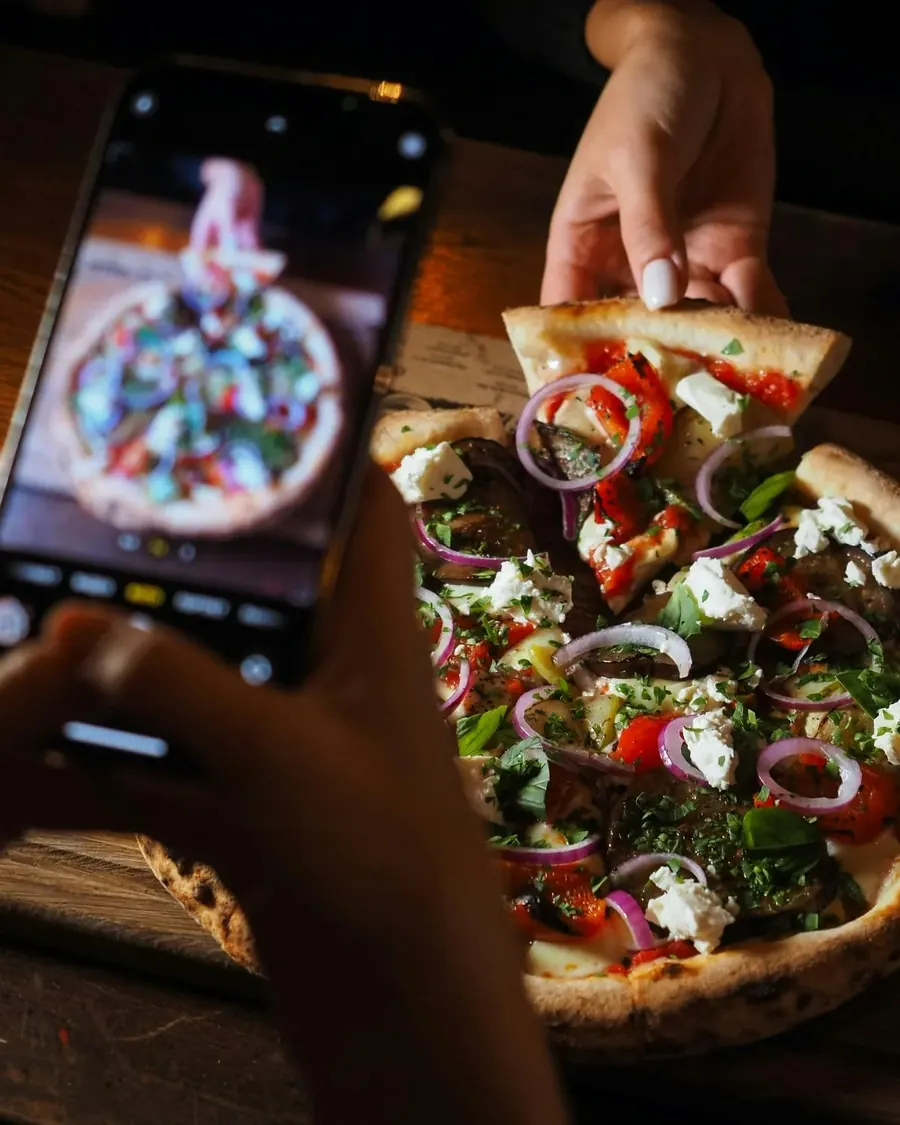 Pizza z czerwoną cebulą i fetą fotografowana telefonem w Villa Toscana Nowy Targ